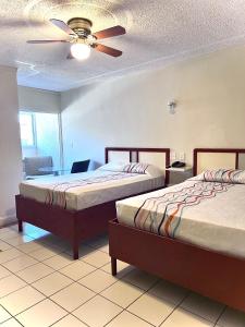 a hotel room with two beds and a ceiling fan at Hotel León in Tijuana