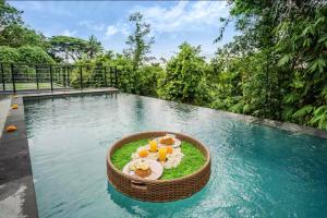 a resort swimming pool with a bowl of food and snacks at Villa De Cupit Ubud Gianyar Bali in Ubud