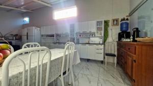 a kitchen with white cabinets and a table and chairs at Pousada Canto das Samambaias in Capitólio