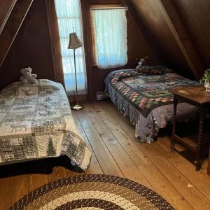 a bedroom with two beds and a table in a room at Adorable Aframe in the White Mountains in Conway