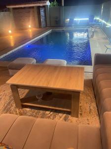 a wooden table in front of a swimming pool at Villa Moderne avec Piscine Privée in Imouzzer du Kandar