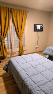 a bedroom with a large bed with yellow curtains at Puerta Sur Apart in Malargüe