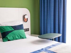 a bedroom with a bed and a blue curtain at Ibis Styles Cayenne Centre Amazonia in Cayenne +78 photos