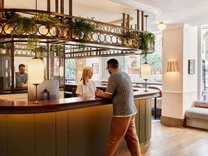 a man and woman standing at a bar in a restaurant at Hyde London City - St Paul's in London