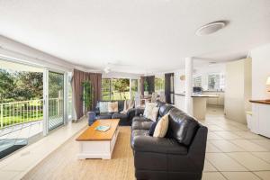 a living room with a black leather couch and a table at Surfside Buddina Beachfront 3bed Apt - Direct Beach Access in Buddina