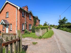 an old brick house with a wooden fence next to a road at Shepherd's Cottage in Bridgnorth
