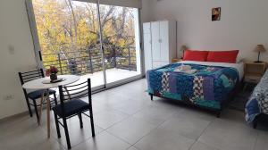 a bedroom with a bed and a table and a balcony at Casa Arpy in Mendoza