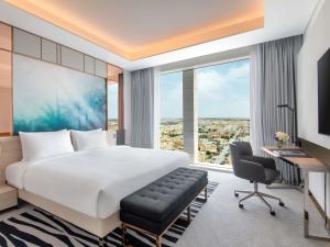 a bedroom with a bed and a desk and a large window at Novotel Riyadh Sahafa in Riyadh