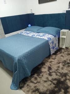 a bed with a blue comforter in a bedroom at QUARTO AZUL com cozinha e piscina só sua in Capão da Canoa +13 photos