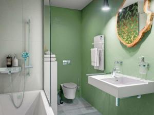 a green bathroom with a sink and a toilet at ibis Styles Bezons Paris La Défense in Bezons