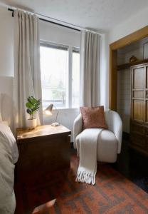 a bedroom with a white chair and a window at Alaskan Hideaway | Cozy & Adventure-Ready in Anchorage