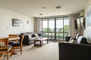 a living room with a couch and chairs and a table at The Anchorage Apartments in Mount Maunganui
