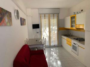 a kitchen with a red couch in a room at Apartment with Pool in Rosolina Mare 57971 in Rosolina Mare