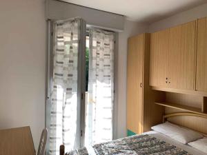 a bedroom with a bed and a window with curtains at Apartment with Pool in Rosolina Mare 57971 in Rosolina Mare