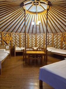 a room with a table and benches in a yurt at Bayalag Resort in Yoliin Hural