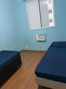 a blue room with two beds and a window at Apto 2 qts em Xerém próximo ao CT do Fluminense in Duque de Caxias