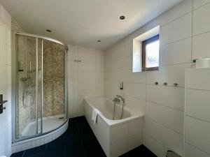 a bathroom with a tub and a shower and a sink at Chalet with Mountain View in Piesendorf +30 photos