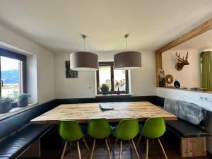a dining room with a wooden table and green chairs at Chalet with Mountain View in Piesendorf