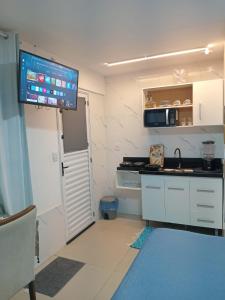a small kitchen with a sink and a tv on the wall at QUARTO AZUL com cozinha e piscina só sua in Capão da Canoa