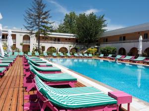 a row of chaise lounge chairs next to a swimming pool at ibis Styles Venus in Venus