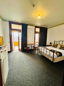 a bedroom with a bed and a desk in a room at Golden Age Hotel in Omeo