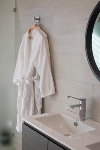 a white robe hanging on a wall next to a sink at Softfoot Farm Luxury Retreats in Hindmarsh Valley +26 photos