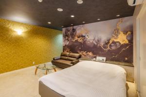 a bedroom with a bed and a couch and a painting at HOTEL Lien in Ashiya