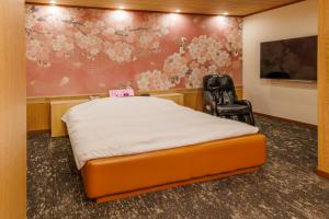 a room with a bed and a chair in it at HOTEL Lien in Ashiya