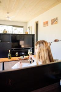 a woman sitting in a chair with a glass of wine at Softfoot Farm Luxury Retreats in Hindmarsh Valley