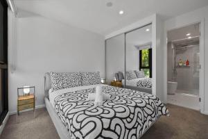 a bedroom with a black and white bed and a bathroom at Central 2b2b with 2 Parkings across largest Mall in Braddon