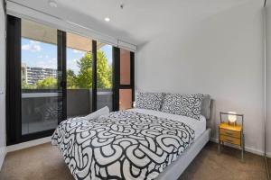 a bedroom with a black and white bed and a window at Central 2b2b with 2 Parkings across largest Mall in Braddon