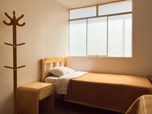 a small room with a bed and a cross on the wall at Ayllu in Huaraz
