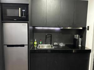a kitchen with a sink and a microwave and a refrigerator at Cloud & Rey condo rentals in Roxas City