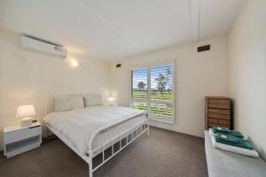 a white bedroom with a bed and a window at Nathan's Place in Whitfield