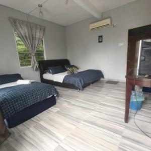 a bedroom with two beds and a television in it at Kurau Stone Chalet in Taiping