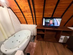 a bathroom with a tub and a tv on a counter at Recanto sol nascentre cabanas in Monte Verde