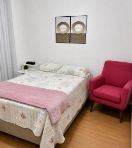 a bedroom with a bed and a pink chair at Apartamento 02 QUARTOS, confortável no coração da Pampulha in Belo Horizonte