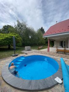 a man in a swimming pool in a yard at Magyar Tenger Pihenőház, for 2-8 person, 105 m2, garden, pool, free parking, 5 min from the Lake, Balatonakarattya in Balatonakarattya