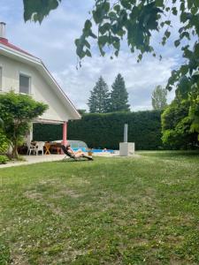 a person laying on a lawn next to a house at Magyar Tenger Pihenőház, for 2-8 person, 105 m2, garden, pool, free parking, 5 min from the Lake, Balatonakarattya in Balatonakarattya