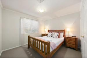 a bedroom with a wooden bed and a window at Palmers Lane Vineyard Cottage in Pokolbin