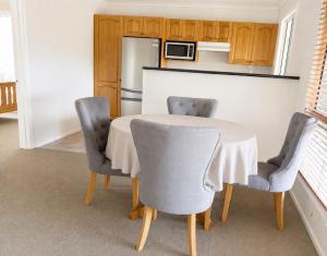 a kitchen with a table with two chairs and a refrigerator at Palmers Lane Vineyard Cottage in Pokolbin