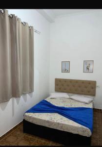 a bedroom with a bed with blue sheets and curtains at Pousada Encanto De Itanhaém in Itanhaém +15 photos