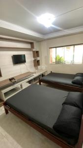 a bedroom with two beds and a tv on a wall at Pousada Encanto De Itanhaém in Itanhaém