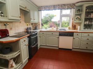 a kitchen with white cabinets and a window at Woolly Welcome in Penzance +26 photos
