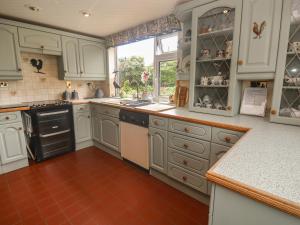 a kitchen with white cabinets and a red tile floor at Woolly Welcome in Penzance