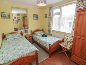a bedroom with two beds and a chair and a window at Woolly Welcome in Penzance