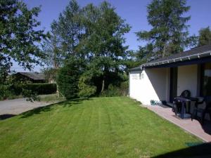 a backyard with a lawn and a white shed at Sunny Cottage with Pool in Purnode