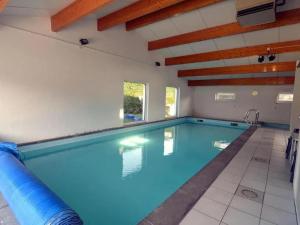 an indoor swimming pool with blue water at Sunny Cottage with Pool in Purnode +25 photos