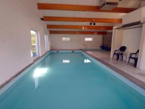a swimming pool in a room with a table and chairs at Sunny Cottage with Pool in Purnode