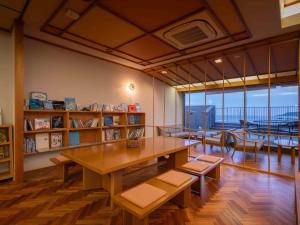 a library with a wooden table and chairs and a large window at Hamabenoyado Kameya in Toba